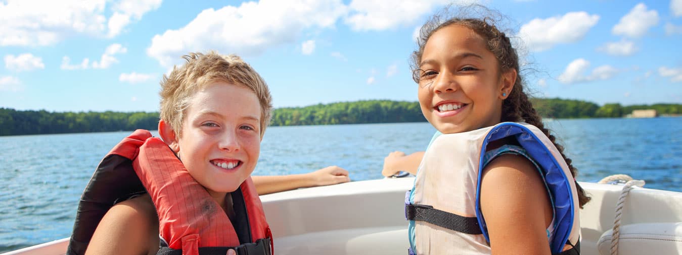 two kids wearing life jackets enjoy a boat ride on oneida lake